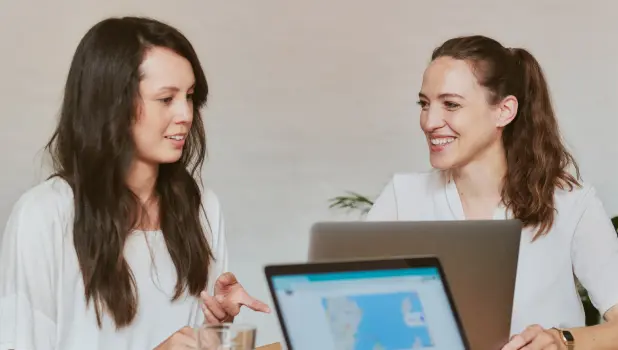 An image of a couple of women looking at laptops